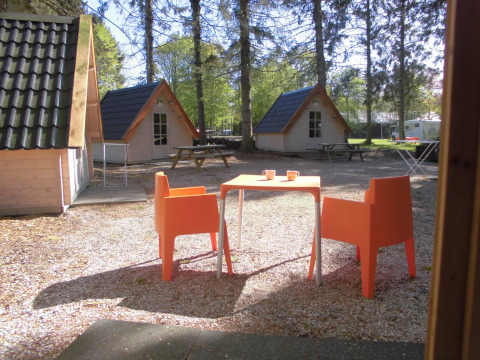 Buitenruimte met oranje stoelen en tafel voor houten huisjes bij Kabouterhuisje, 't Urkerbos, Nederland.