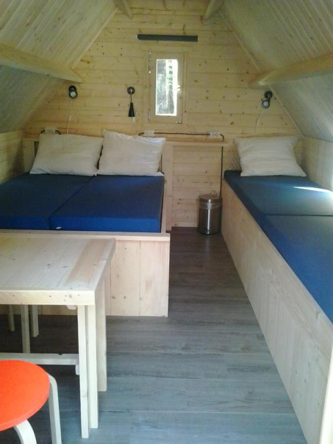 Interiør af et hyggeligt træhus med to senge, bord og stole på Vakantiepark 't Urkerbos i Holland.
