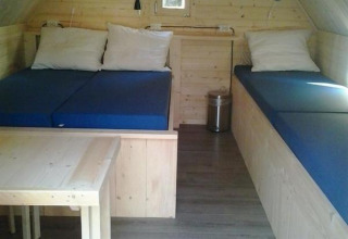 Interiør af et hyggeligt træhus med to senge, bord og stole på Vakantiepark 't Urkerbos i Holland.