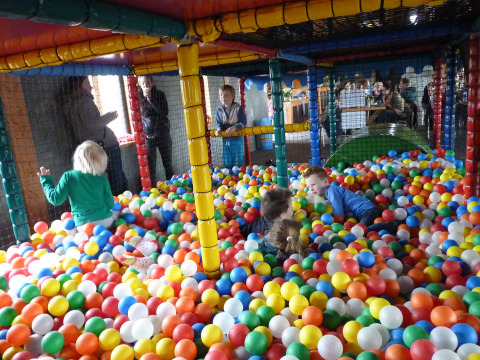 Niños jugando en una piscina de bolas en un parque infantil cubierto en Camping Nieuw Romalo, Gelderland.