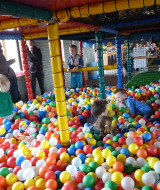 Niños jugando en una piscina de bolas en un parque infantil cubierto en Camping Nieuw Romalo, Gelderland.