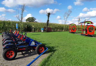 Toy pedal cars and a red play train on grass at Camping Nieuw Romalo holiday park, Gelderland, Netherlands