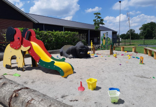 Spielplatz mit Rutsche, Tierfiguren und Sandspielzeug im Ferienpark Camping Nieuw Romalo, Gelderland, Niederlande.