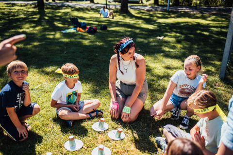 Kinderen en een vrouw spelen een groepsspel op het gras bij Eurocamping Vessem BV in Noord-Brabant, Nederland.