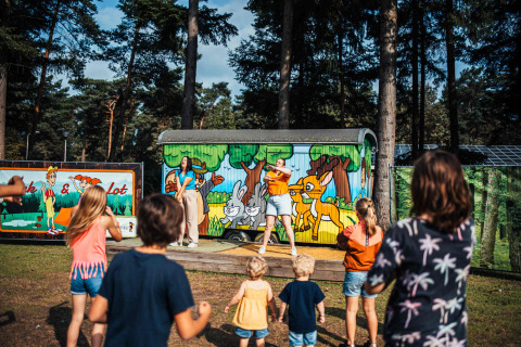 Niños participan en una actividad al aire libre frente a una cabaña pintada en Eurocamping Vessem, Brabante Norte.