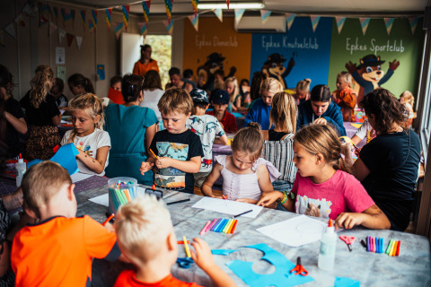 Children do arts and crafts at a long table during an indoor activity at Eurocamping Vessem BV in the Netherlands.