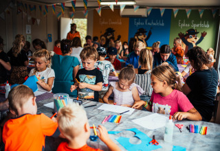 Children do arts and crafts at a long table during an indoor activity at Eurocamping Vessem BV in the Netherlands.