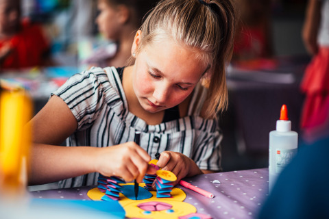 Una niña hace manualidades en una mesa del Eurocamping Vessem BV, parque de vacaciones en Brabante Septentrional.