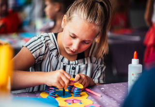 Een kind doet knutselwerk aan een tafel op Eurocamping Vessem BV, een vakantiepark in Noord-Brabant.