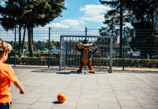 Niño patea un balón hacia una mascota en la portería en Eurocamping Vessem, Brabante Septentrional, Países Bajos.