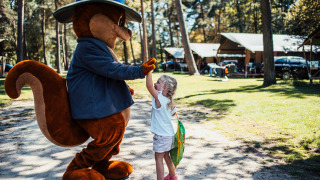 Niña dando un choca esos cinco a una mascota de ardilla en el camping Eurocamping Vessem en los Países Bajos.