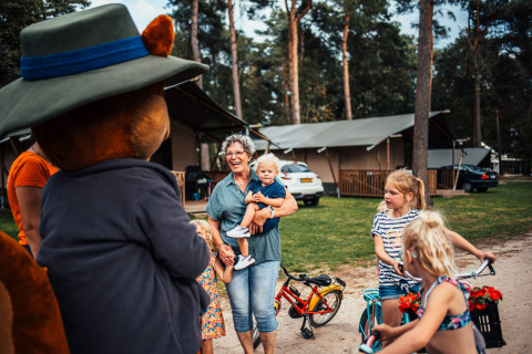 En familie nyder deres ophold på Eurocamping Vessem BV i Nord-Brabant, med børn og maskot på campingpladsen.