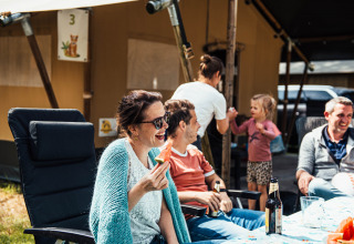 Familie nyder camping på Eurocamping Vessem BV i Nordbrabant, Holland, med mad og drikke udenfor.