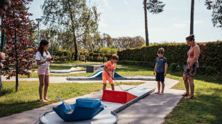 Familia jugando al minigolf en el parque de vacaciones Eurocamping Vessem BV en North-Brabant, Países Bajos.