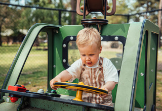 Young boy plays in a green play vehicle at Eurocamping Vessem BV holiday park, North-Brabant, Netherlands.
