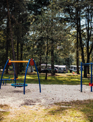 Parque infantil entre árboles en Eurocamping Vessem BV, parque vacacional familiar en Brabante Septentrional.
