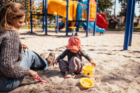 An adult and child play in the sand at a playground in Eurocamping Vessem BV, North Brabant, Netherlands.