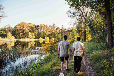 Twee personen wandelen hand in hand bij een meer in Eurocamping Vessem BV, Noord-Brabant, Nederland.