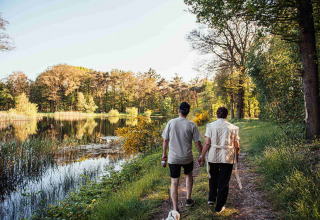 Twee personen wandelen hand in hand bij een meer in Eurocamping Vessem BV, Noord-Brabant, Nederland.