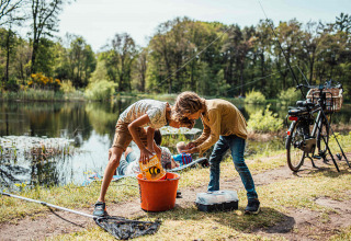 Dos niños pescando junto a un lago en Eurocamping Vessem BV, un parque vacacional en North-Brabant, Países Bajos.