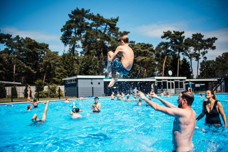 Kinder und Erwachsene genießen einen Sommertag im Außenpool bei Eurocamping Vessem BV, Niederlande.