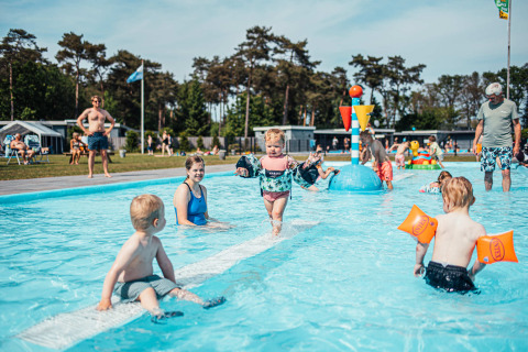 Niños juegan y nadan en una piscina poco profunda en Eurocamping Vessem BV, un parque vacacional en Brabante Septentrional, Países Bajos.