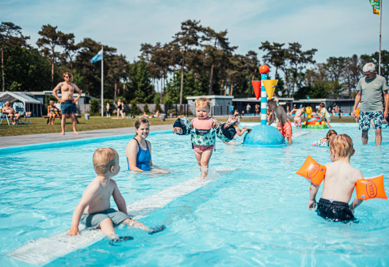 Børn leger og svømmer i en lav swimmingpool på Eurocamping Vessem BV, en feriepark i Nordbrabant, Holland.