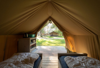 Vue intérieure d'une tente safari Duolodge à Eurocamping Vessem BV, avec deux lits et une terrasse boisée.