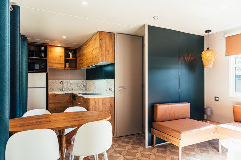Moderne lodge med træ- og lædermøbler, åbent køkken og spiseområde på Eurocamping Vessem BV i Holland.