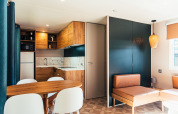 Interno di una moderna lodge con cucina in legno e zona pranzo a Eurocamping Vessem BV, Paesi Bassi.
