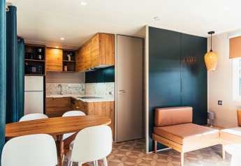 Interno di una moderna lodge con cucina in legno e zona pranzo a Eurocamping Vessem BV, Paesi Bassi.