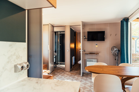 Interiør af en moderne Boslodge på Eurocamping Vessem BV i Holland med spisebord og tv på væggen.