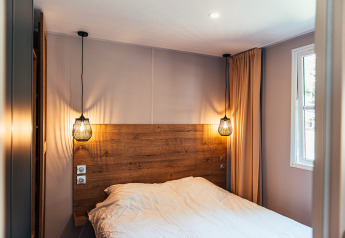 Camera moderna al Boslodge, Eurocamping Vessem BV, Paesi Bassi, con testiera in legno e luci a sospensione.