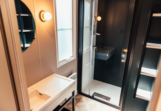 Baño moderno en Boslodge de Eurocamping Vessem BV, Países Bajos, con espejo, lavabo y ducha.