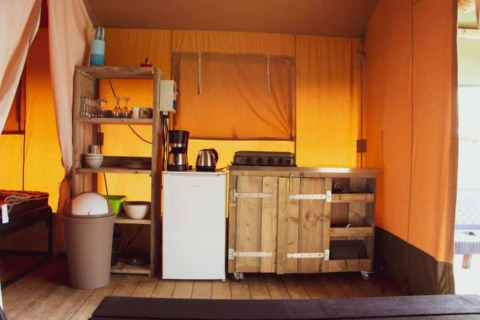 Vista interior de una tienda Safari en Eurocamping Vessem BV, Países Bajos, con cocina y estanterías.