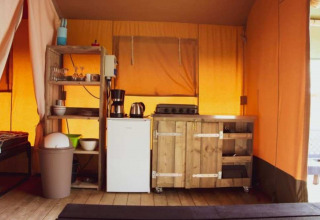 Vista interior de una tienda Safari en Eurocamping Vessem BV, Países Bajos, con cocina y estanterías.
