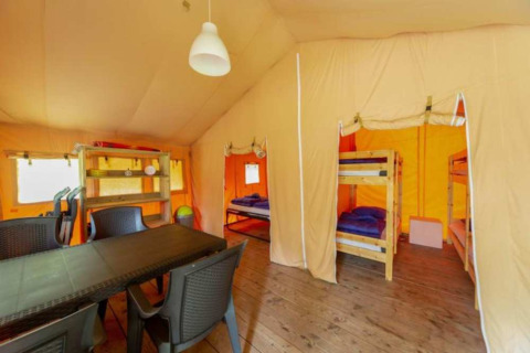 Vista interior de la tienda Safari en Eurocamping Vessem BV, Países Bajos, con literas y mesa de comedor.