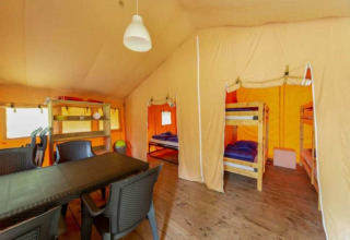 Vista interior de la tienda Safari en Eurocamping Vessem BV, Países Bajos, con literas y mesa de comedor.
