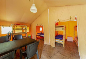 Vista interior de la tienda Safari en Eurocamping Vessem BV, Países Bajos, con literas y mesa de comedor.