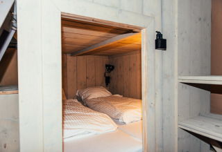 Interior de una tienda safari con cama doble y paredes de madera en Eurocamping Vessem BV, Países Bajos.