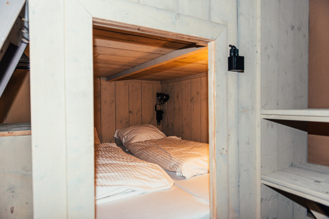 Interior de una tienda safari con cama doble y paredes de madera en Eurocamping Vessem BV, Países Bajos.