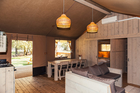 Interior de una tienda safari con muebles de madera y comedor en Eurocamping Vessem, Países Bajos.