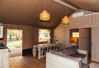 Interno di una tenda safari con arredi in legno e zona pranzo all’Eurocamping Vessem, Paesi Bassi.