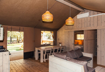 Indersiden af et moderne safaritelt med træmøbler og hængende lamper på Eurocamping Vessem i Holland.
