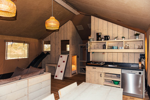 Interior de tienda safari con cocina y sala en Eurocamping Vessem BV, Países Bajos.
