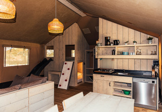Interior de tienda safari con cocina y sala en Eurocamping Vessem BV, Países Bajos.