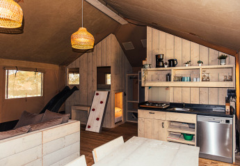 Interior de tienda safari con cocina y sala en Eurocamping Vessem BV, Países Bajos.