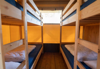 Interior view of a safari tent with four bunk beds and wooden floor at Eurocamping Vessem BV, Netherlands.