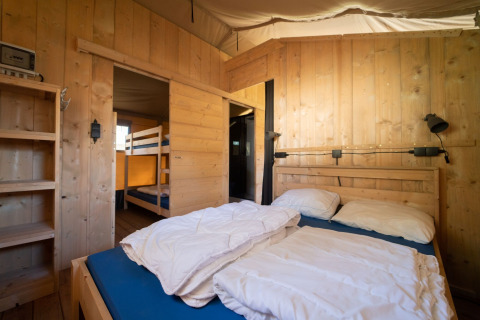 Interno di una tenda safari con letto matrimoniale e letti a castello presso Eurocamping Vessem BV nei Paesi Bassi.