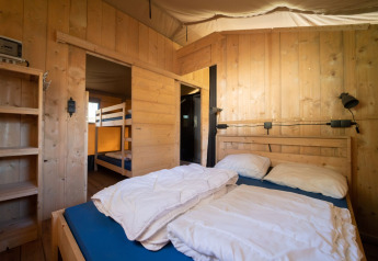 Interno di una tenda safari con letto matrimoniale e letti a castello presso Eurocamping Vessem BV nei Paesi Bassi.